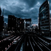 曇り空と日が落ちた新宿駅前の夜景、高層ビル群と夜間の都市風景の写真