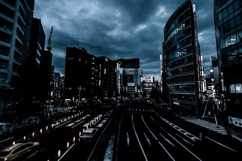 曇り空と日が落ちた新宿駅前の夜景、高層ビル群と夜間の都市風景
