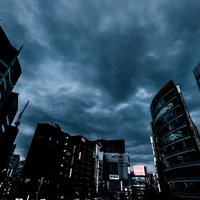 曇り空の中に聳える新宿のビル群の夕暮れ風景の写真