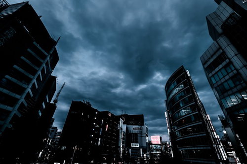 曇り空の中に聳える新宿のビル群の夕暮れ風景