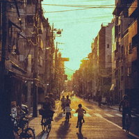 夕焼けに照らされた住宅街を自転車で走る子どもたちの写真