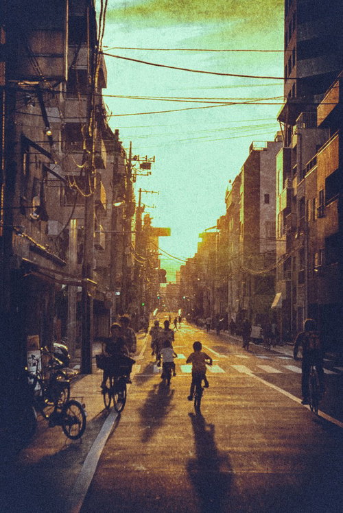 夕焼けに照らされた住宅街を自転車で走る子どもたち