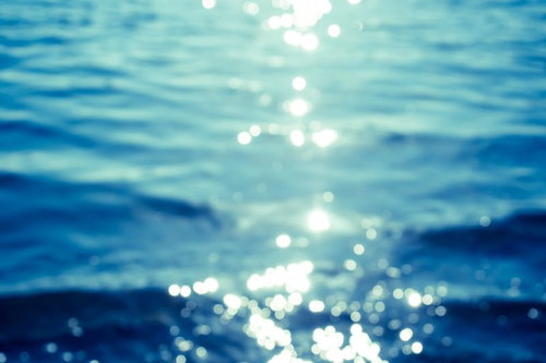 水面に日光が反射して多数の白い光点が散らばる海辺