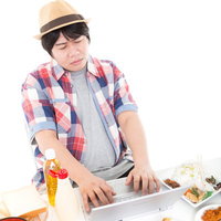 納期に追われ、ついつい出前を取り過ぎてしまったノートパソコンを操作する編集者の写真