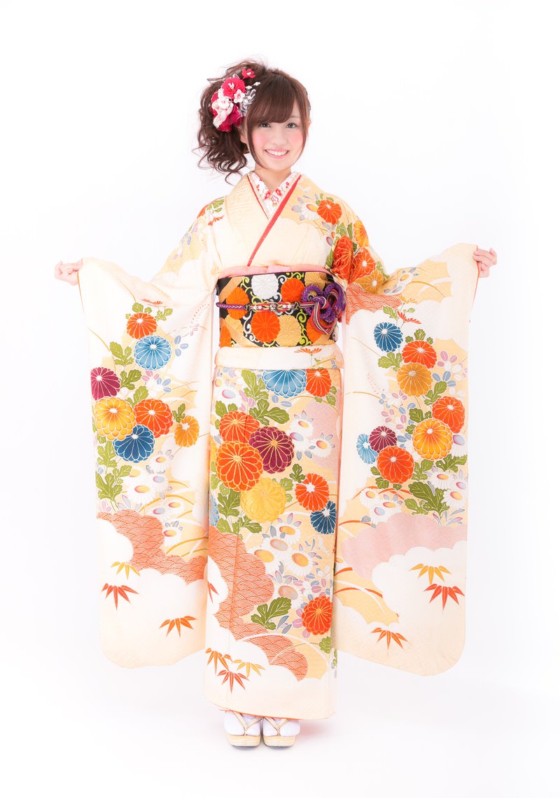 クリーム色の振袖で両袖を広げて笑顔で立つ女性［モデル：河村友歌］