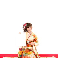 クリーム色と赤の振袖で新年の抱負を語る着物姿の女性の写真