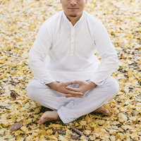 落ち葉に囲まれた修行中の男性が瞑想する姿の写真