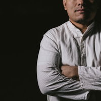 暗闇の中で腕を組み凝視する白いシャツの男性が深い思考に耽るの写真