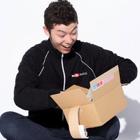 欲しいものリストの商品が届いた時にダンボール箱を開封して喜ぶ男性の写真