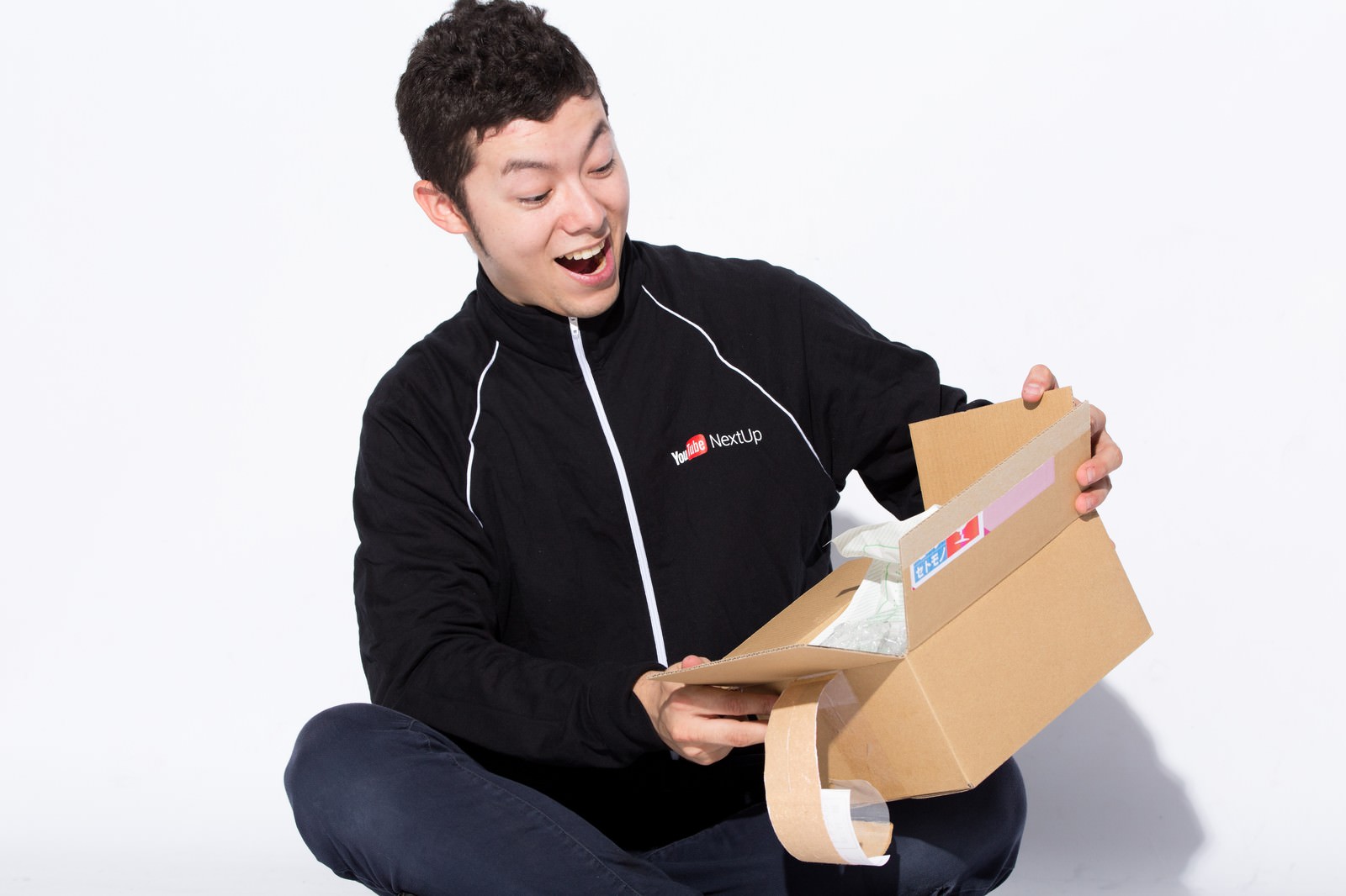 ダンボール箱を喜んで受け取る黒いジャケット姿の男性［モデル：けんたさん］