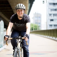 都市の橋でロードバイクに乗る白いヘルメットの男性の写真