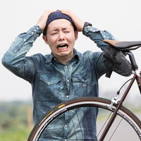 自転車がパンクして叫ぶ男性、ロードバイクの故障で困った表情の写真