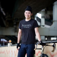 高架下でロードバイクの休憩を楽しむ男性の笑顔の写真