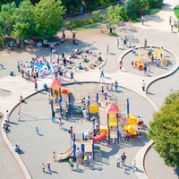 遊具のある公園に集まる親子連れの風景の写真