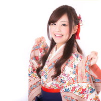 着物の袖を持った笑顔の成人女性、白地の花柄着物と赤い帯の写真