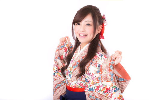 着物の袖を持った笑顔の成人女性、白地の花柄着物と赤い帯