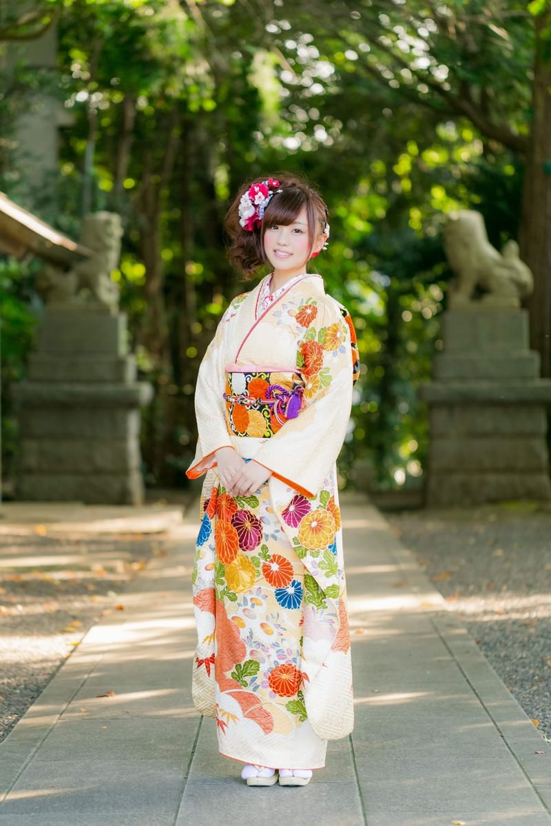 神社の参道で白い振袖を着た女性が立っている。帯と髪飾りが鮮やか。［モデル：河村友歌］