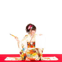 新年の抱負を筆で書く振袖姿の着物美女の書き初めの写真