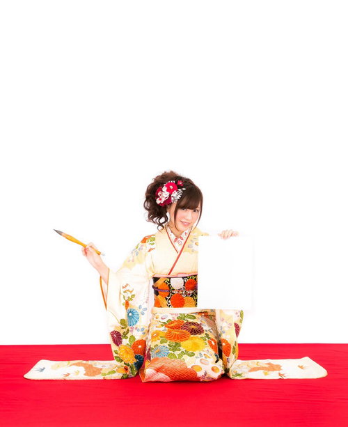 新年の抱負を筆で書く振袖姿の着物美女の書き初め