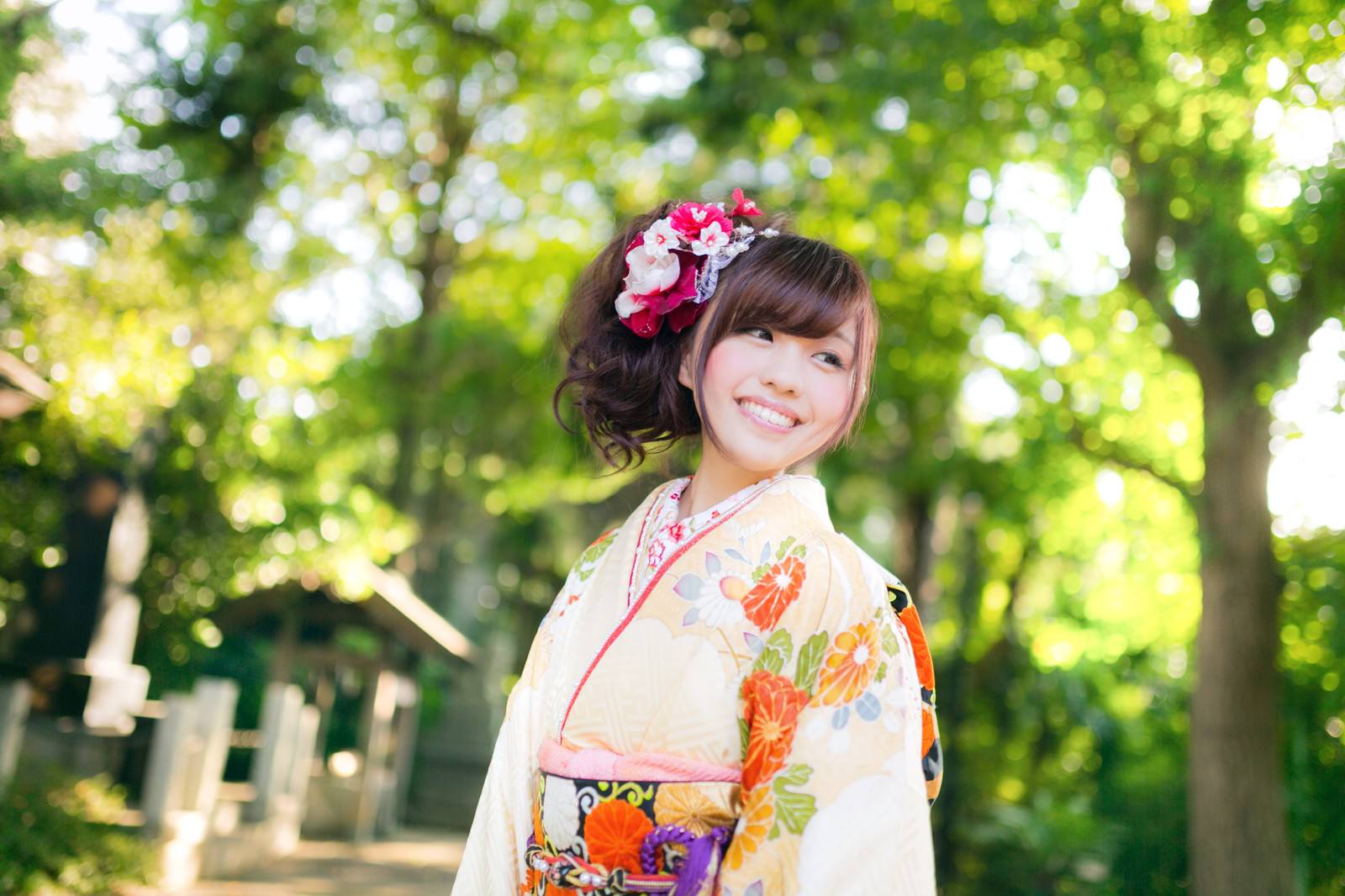 神社の緑の背景で振袖姿で笑う女性［モデル：河村友歌］