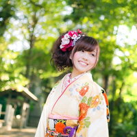 新緑の神社境内で振袖姿の女性の写真
