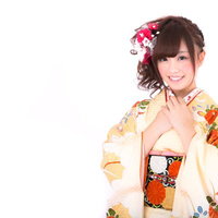 黄色い着物に赤い髪飾りをした女性が胸に手を当てて驚く表情の写真