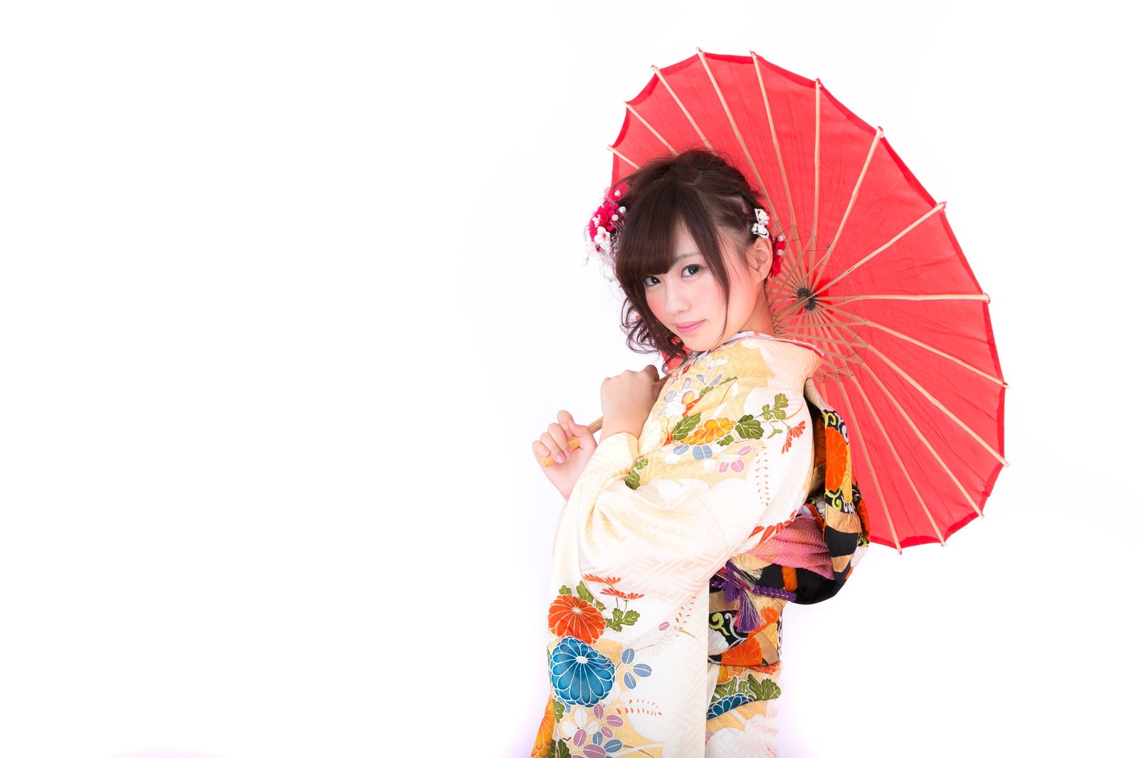 赤い和傘を差す振袖姿の女性が花飾りを挿した髪で微笑んでいる［モデル：河村友歌］
