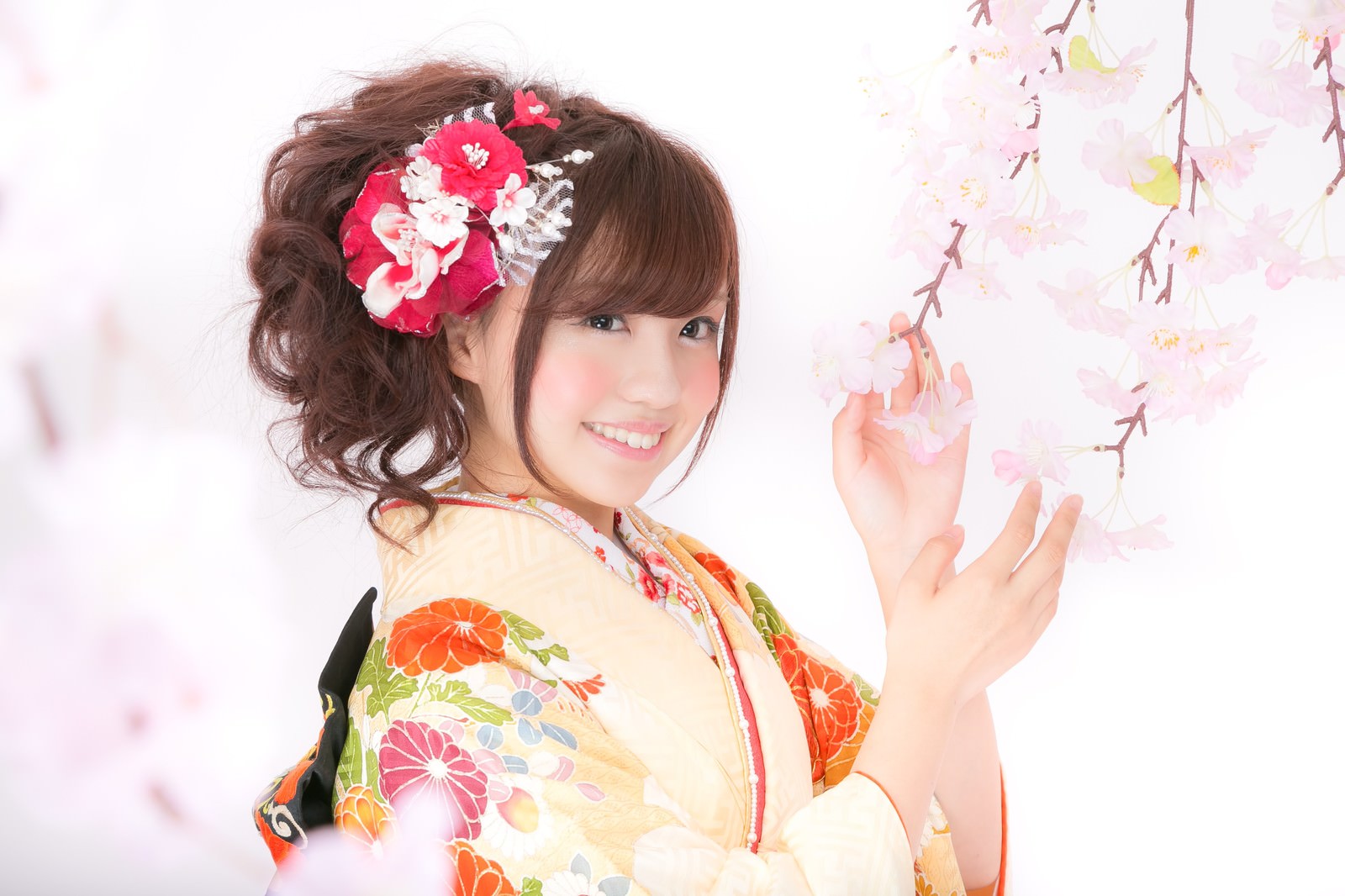 桜の前で振袖姿の笑顔の女性［モデル：河村友歌］