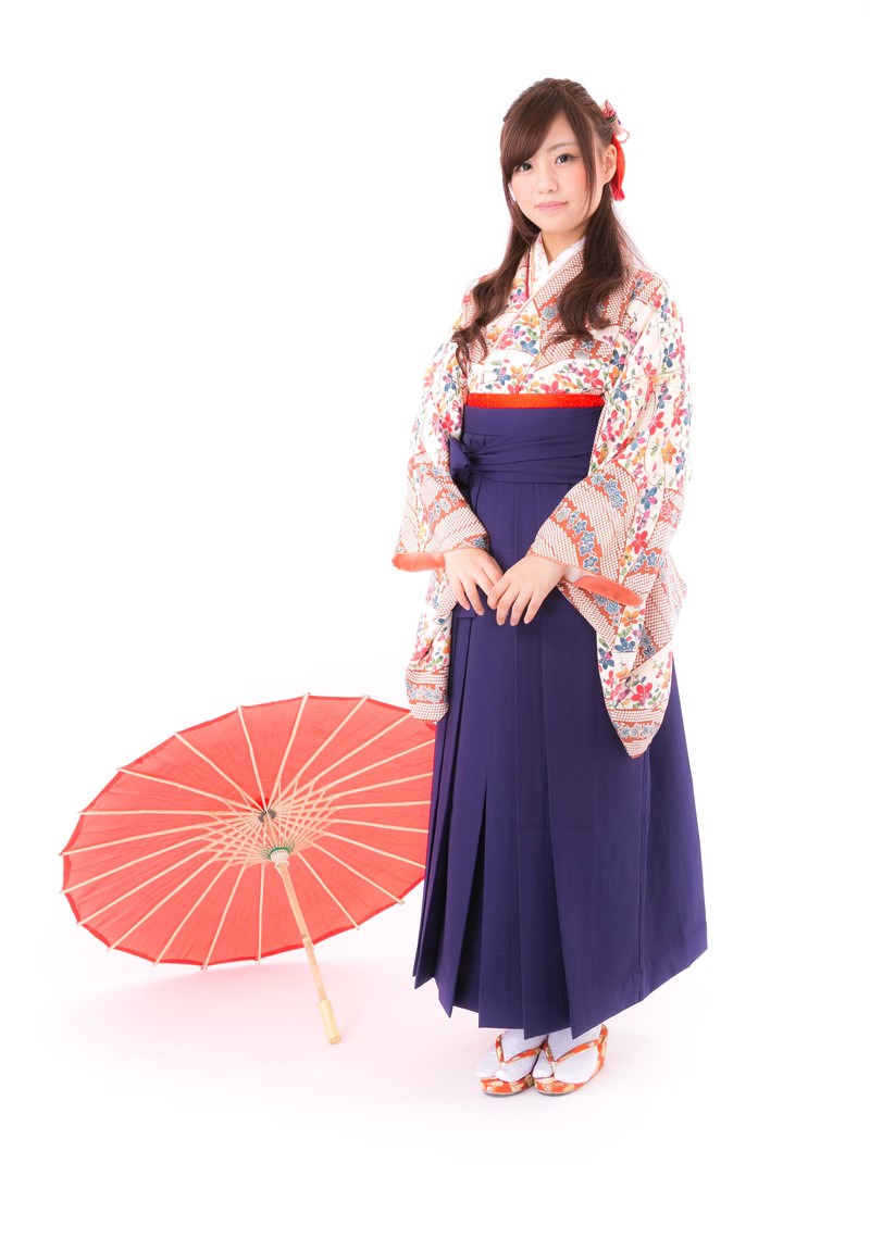 赤い和傘を持つ着物と袴姿の女性が正面を向いて立っている［モデル：河村友歌］