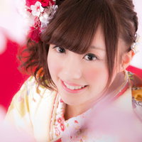 桜を見上げる着物美女、赤とピンクの髪飾りが映える春の成人式の写真