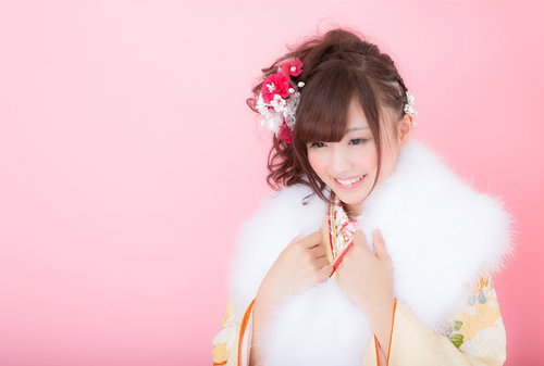 成人式を迎えた二十歳の女性、紅白の髪飾りと白いファーストール姿