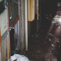 廃墟と化した民宿の暗い裏口 木製扉と錆びた壁の劣化の写真