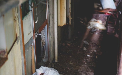 廃墟と化した民宿の暗い裏口 木製扉と錆びた壁の劣化