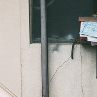 溜まった郵便受けと配線、古い建物のコンクリート壁の写真