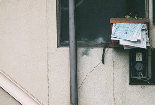 溜まった郵便受けと配線、古い建物のコンクリート壁