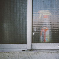 老朽化したアパートの窓に置かれた洗剤ボトルの写真