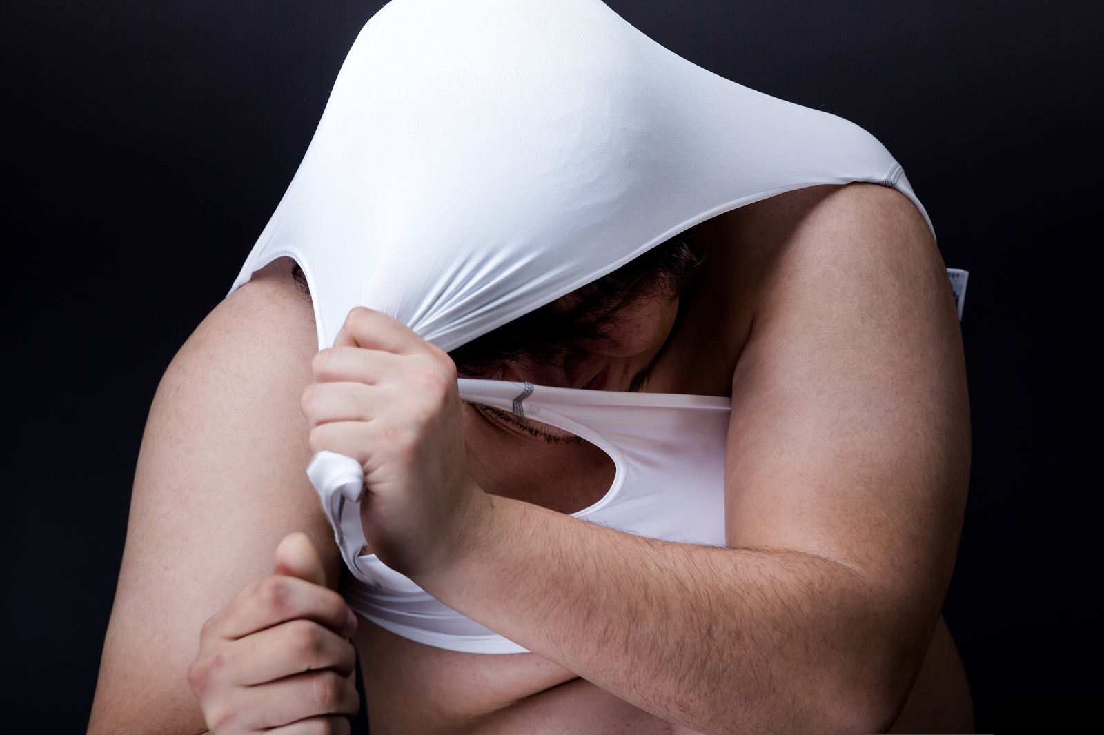 白い衣装を引きちぎろうとする体型の男性が目線を下げている［モデル：あまのじゃく］