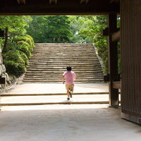 岡山城の城門をくぐって石段を駆け上がるAD男性の写真