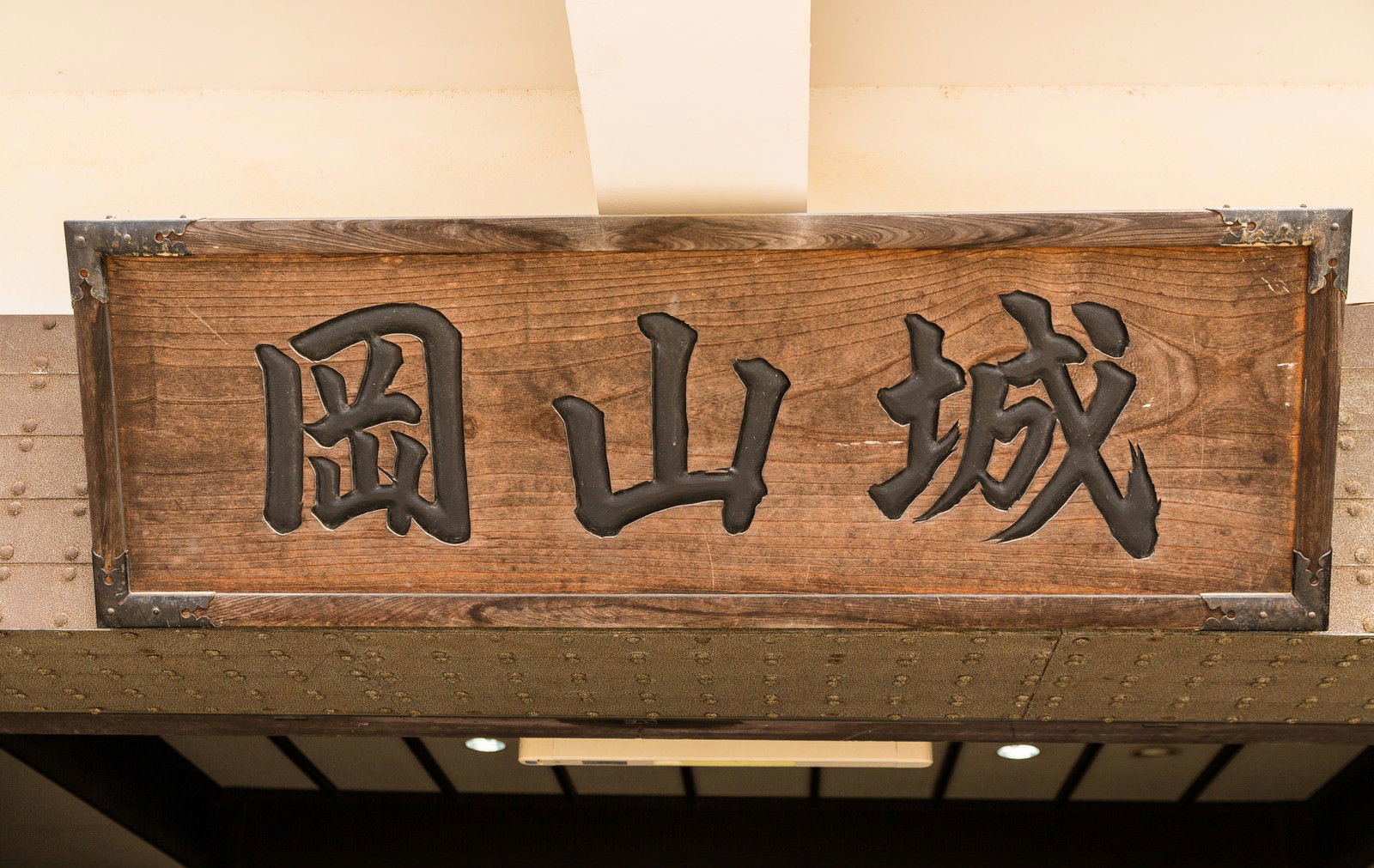 岡山城と書かれた茶色い木製の彫刻看板