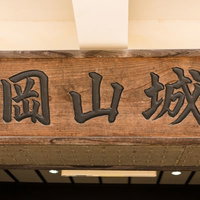 岡山城の名前が彫られた木製の看板 - 城跡観光施設の歴史的標識の写真