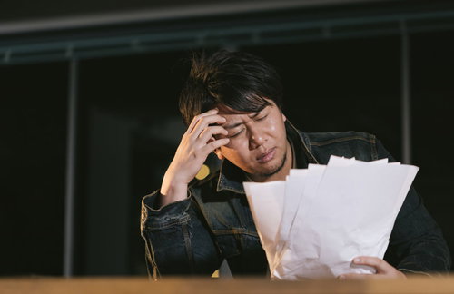 デスクで出来上がった原稿を見て頭を抱える男性ライター