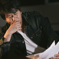 深夜の校閲業務で原稿をチェックする男性の集中力と仕事風景の写真