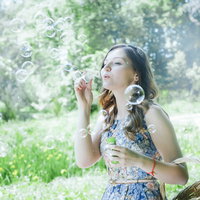 公園でシャボン玉を吹くロシア人女性の夏の散歩風景の写真