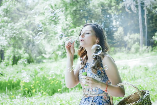 公園でシャボン玉を吹くロシア人女性の夏の散歩風景