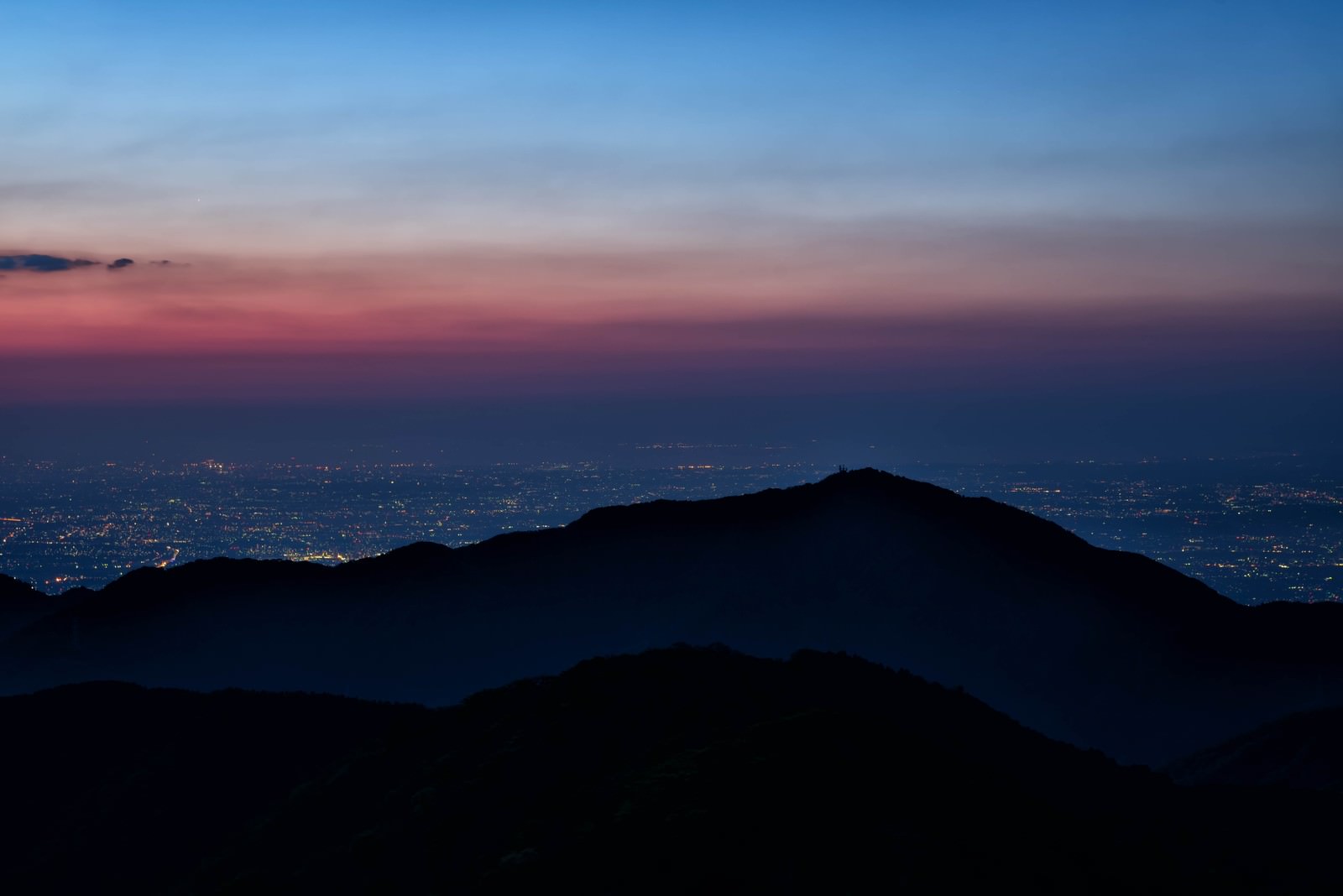 夕暮れ時の大山のシルエットと眼下に広がる街の夜景