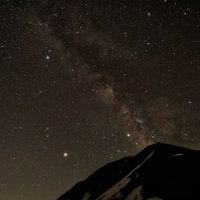 常念岳の山頂から立ち上がる天の川と星空の夜間風景の写真