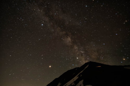 常念岳の山頂から立ち上がる天の川と星空の夜間風景