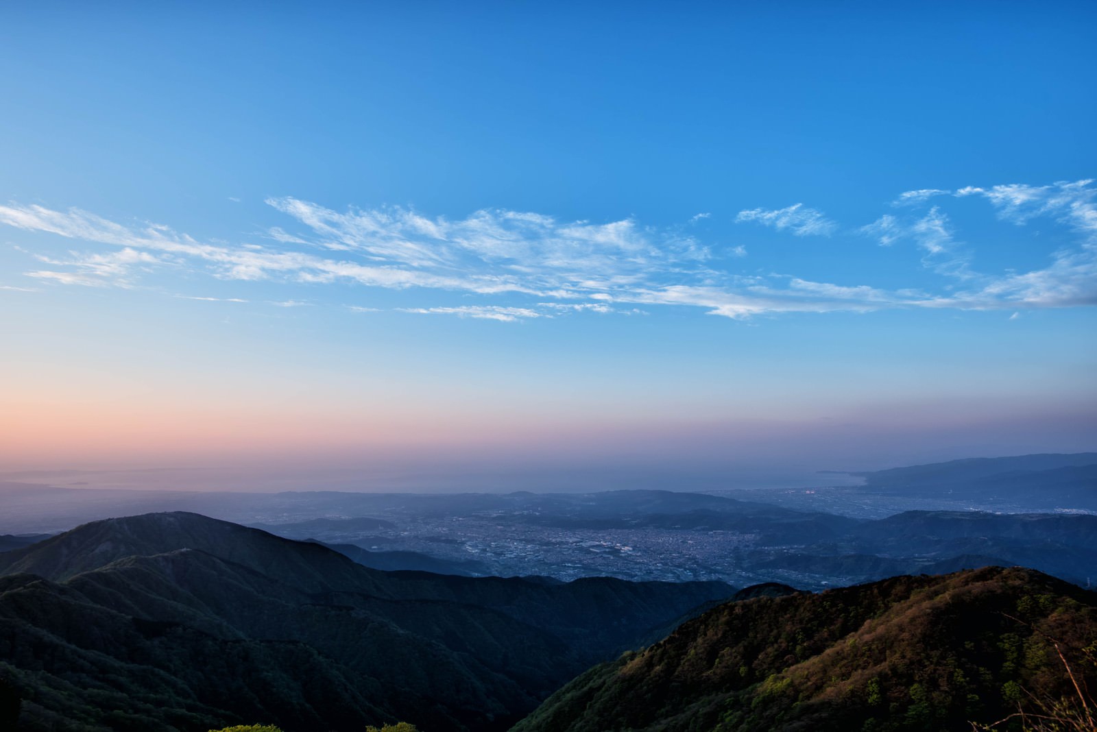 朝焼けの空と霞に包まれた相模湾の山峰と街並みの風景