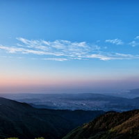 朝焼けと霞がかかる相模湾の山峰と街並みの風景の写真