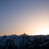 薄明の中で浮かぶ槍ヶ岳の穂先と朝焼けの山岳風景の写真